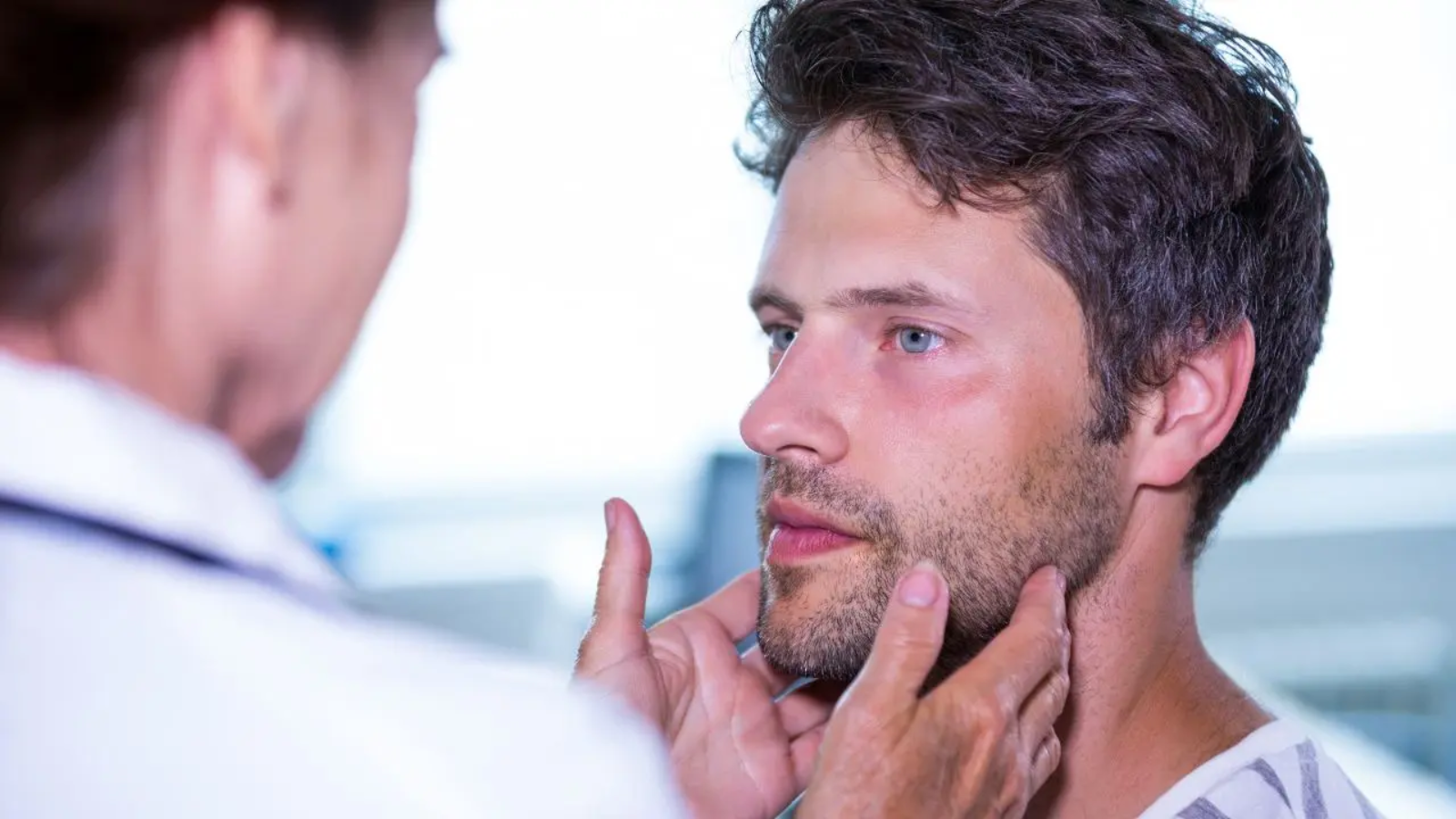Una doctora examina un bulto en el cuello de un paciente