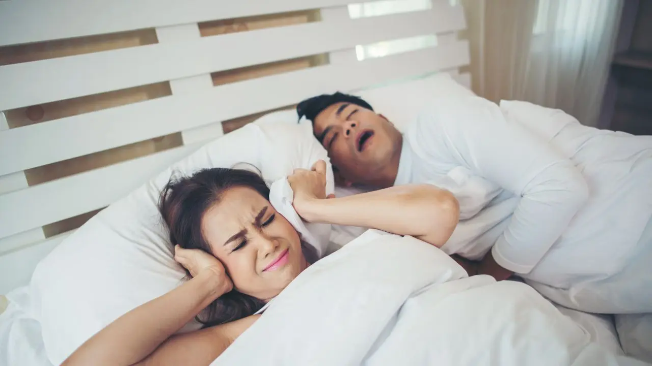 Una mujer se tapa con la almohada porque su marido ha empezado a roncar más en verano