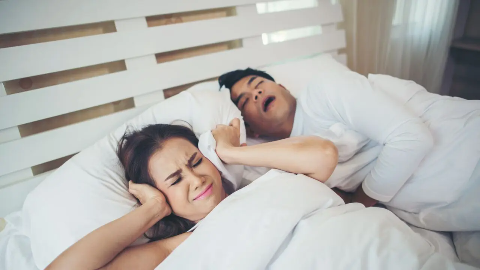 Una mujer se tapa con la almohada porque su marido ha empezado a roncar más en verano