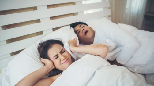 Una mujer se tapa con la almohada porque su marido ha empezado a roncar más en verano